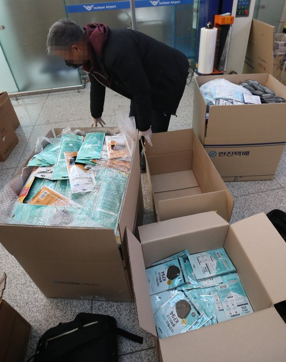 5일 오전 인천국제공항 1터미널에서 공항 이용객들이 중국으로 가져갈 마스크를 마스크 상자에서 택배회사 상자로 옮겨 담고 있다. [연합뉴스]