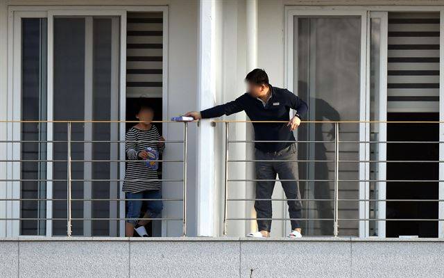 중국 후베이성 우한시에서 지난달 31일 전세기로 귀국해 임시 생활시설인 충북 진천군 국가공무원인재개발원에서 격리 생활을 하고 있는 교민들이 9일 오후 발코니 분리대를 사이에 두고 과자를 건네고 있다. 진천=고영권 기자