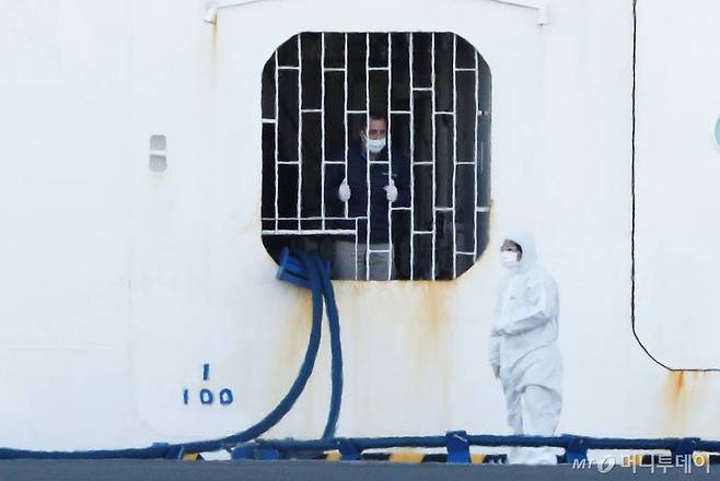 10일 일본 요코하마 항구에 정박 중인 '다이아몬드 프린세스'에서 한 선원(왼쪽)이 보호장비를 갖춘 근로자에게 말을 걸고 있다. 지난달 20일 이곳을 출발했던 이 크루즈선은 중간에 홍콩에서 내린 홍콩인이 신종 코로나 바이러스 확진 판정을 받으면서, 바이러스 확산 우려로 출발지로 돌아온 후에도 승객(승무원 포함) 전원이 내리지 못하고 있다. 약 3700명의 승객 중 확진자는 이날 60명이 늘면서 총 130명이 됐다. / 사진제공=로이터