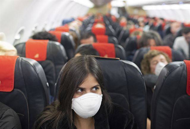 지난 21일 이스라엘에서 이탈리아로 향하는 비행기에 탑승한 승객들이 마스크를 착용한 채 좌석에 앉아 있다. 이스라엘은 오는 24일부터 14일 이내 한국과 일본을 방문한 모든 외국인에 대해 입국을 금지한다. EPA 연합뉴스