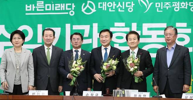 24일 오전 서울 여의도 국회에서 열린 바른미래당-대안신당-민주평화당 합당을 위한 수임기관 합동회의에서 당 대표들이 꽃다발을 든 채 참석자들과 기념촬영 하고 있다. (사진=연합뉴스)