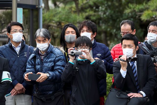 15일 일본 도쿄 외곽 하무라에서 시민들이 마스크를 쓴 채 2020년 도쿄올림픽 성화봉송 리허설을 구경하기 위해 모여 있다. 하무라=로이터 연합뉴스