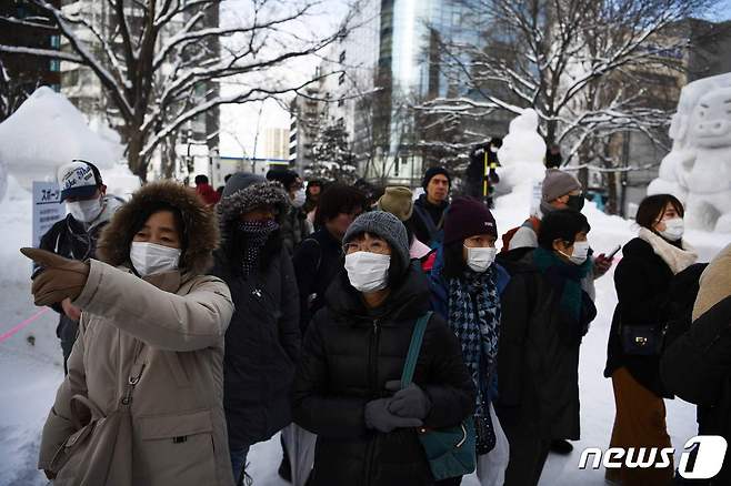 마스크를 쓴 관람객들이 일본 홋카이도(北海道) 삿포로(札晃) 눈 축제 현장을 둘러보고 있다. © AFP=뉴스1
