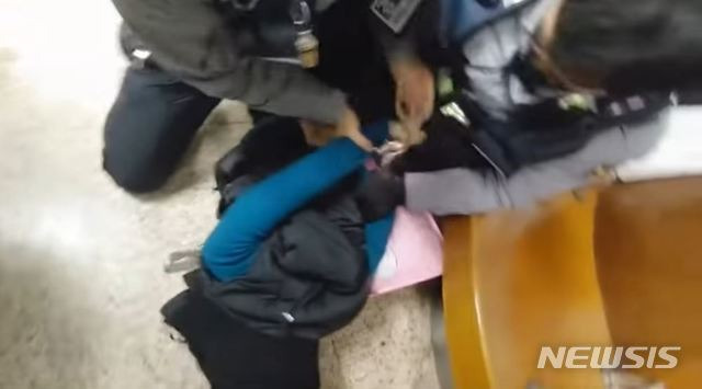[서울=뉴시스]지난달 서울 잠실역에서 경찰 두명이 한 여성의 등 뒤로 수갑을 채우고 있다. 2020.03.04. (사진=유튜브 캡쳐) photo@newsis.com
