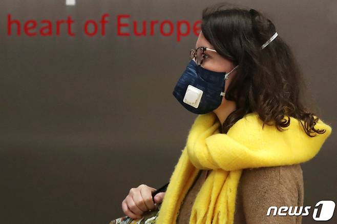 벨기에 브뤼셀 국제공항에서 한 여성 승객이 마스크를 쓴 채 "유럽의 심장'이라 쓰인 표어를 지나고 있다. © 로이터=뉴스1