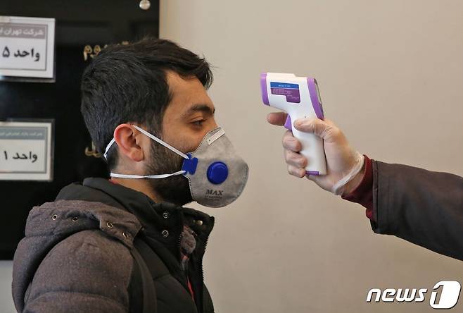 이란 테헤란에서 건물에 들어서는 한 이란인의 체온을 측정하고 있다. © AFP=뉴스1