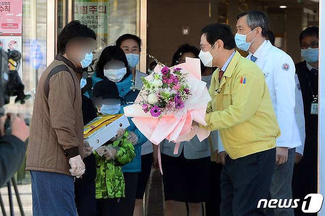 11일 오후 광주 남구 덕남동 빛고을전남대병원에서 이용섭 광주시장이 신종 코로나바이러스 감염증(코로나19) 완치 대구 출신 가족에게 꽃다발을 건네고 있다. 이날 퇴원한 가족(4명)은 코로나19 확진 이후 자가격리돼 있다가 지난 4일 빛고을전남대병원으로 이송돼 치료를 받아왔다. 2020.3.11/뉴스1 © News1 한산 기자