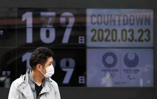 23일 일본 도쿄에서 마스크를 쓴 시민이 올림픽 개막 카운트다운 전광판 앞을 지나고 있다. 로이터 연합뉴스