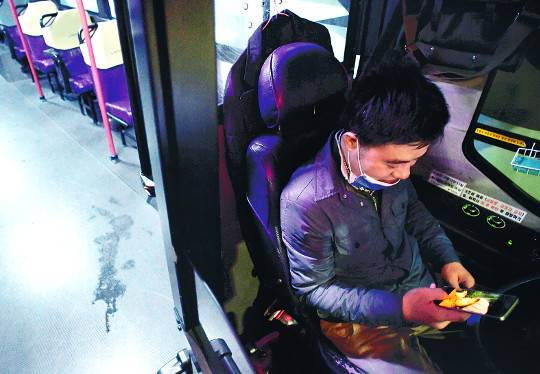 임덕호씨가 지난 19일 새벽 마을버스 운행 중 잠시 쉬는 동안 아이들의 사진을 바라보며 미소짓고 있다.