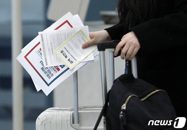 (인천공항=뉴스1) 안은나 기자 = 독일 프랑크푸르트에서 온 입국자가 28일 인천국제공항에서 검역확인증을 들고 별도 교통편을 이용하기 위해 이동하고 있다. 정부는 이날부터 유럽과 미국 입국자 중 신종 코로나바이러스 감염증(코로나19) 증상이 없어 숙소로 가는 이들에게 승용차를 이용한 귀가를 적극 권장하고 승용차 이용이 어려울 경우 전용 버스와 열차 등 교통편을 지원한다. 2020.3.28/뉴스1
