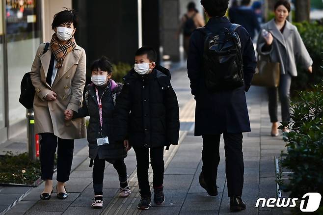 지난 6일 마스크를 착용한 어머니(왼쪽)와 아들·딸 등 가족이 일본 도쿄 시내를 걸어가고 있다.  © AFP=뉴스1