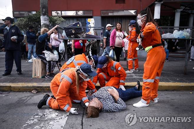 은행 앞에서 기다리다 실신한 한 노인을 구급대원들이 살펴보고 있다. [EPA=연합뉴스]