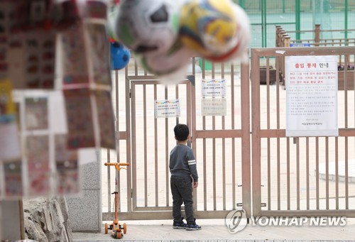 31일 오후 서울 용산구 한 초등학교에서 한 어린이가 닫혀진 문을 바라보고 있다. [사진 출처=연합뉴스]