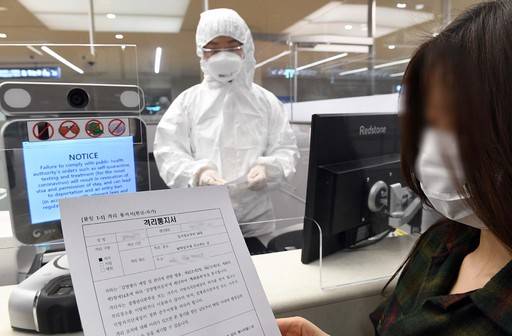 지난 8일 방호복을 입은 인천국제공항 출입국 외국인청 입국심사관이 유증상자 전용 입국심사대에서 입국자에게 자가격리 지침을 설명하고 있다. 인천공항=뉴시스