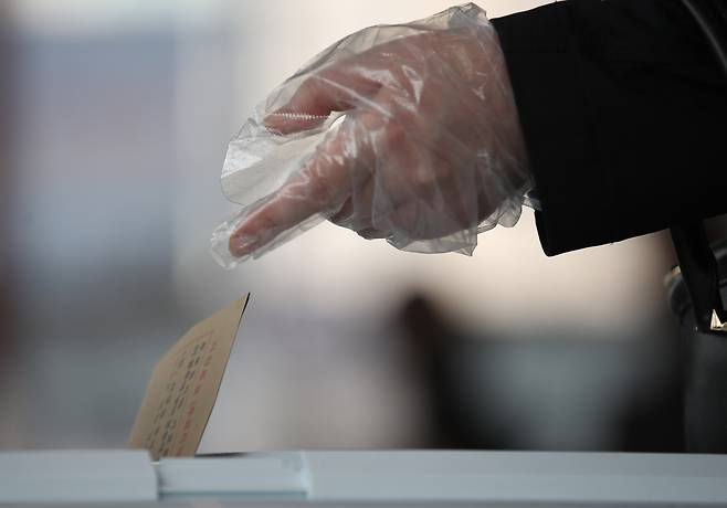 한 유권자가 비닐장갑을 착용하고 투표용지를 투표함에 넣고 있다. 연합뉴스 제공