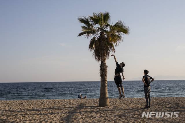 [알리모스=AP/뉴시스] 28일 그리스 아테네 외곽 알리모스 지역의 해변에서 한 청년이 야자수에 손을 뻗으며 뛰어오르고 있다. 유럽 국가들이 신종 코로나바이러스 감염증(코로나19) 봉쇄 완화를 위한 초읽기에 들어간 가운데 관광산업 국가인 그리스가 여름휴가 준비에 나섰다. 해리 테오카리스 그리스 관광부 장관은 29일(현지시간) BBC와의 인터뷰에서 "우리는 진심으로 사람들이 그리스에 오길 바란다"고 말했다. 2020.4.29.