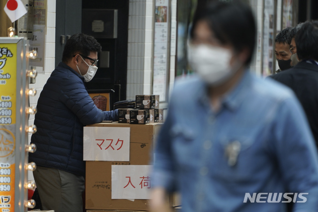 [도쿄=AP/뉴시스]일본 도쿄에서 지난 22일 마스크를 착용한 남성이 '마스크 입고'라고 적힌 종이를 박스에 붙이고는 입고 된 마스크를 꺼내 놓고 있다. 2020.04.23.