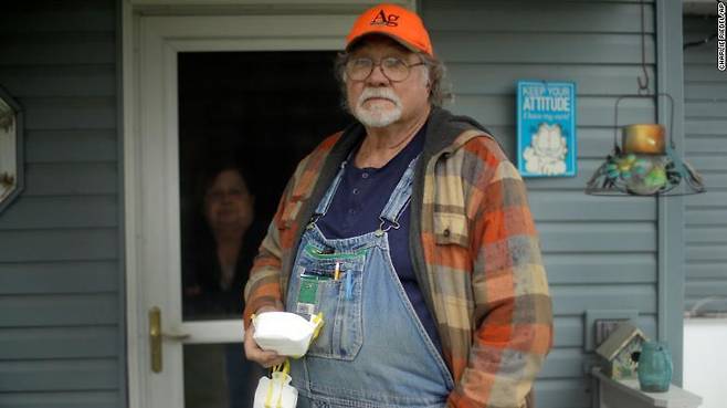 자신의 집 앞에 마스크를 들고 서 있는 캔자스 주 농부 데니스 런크