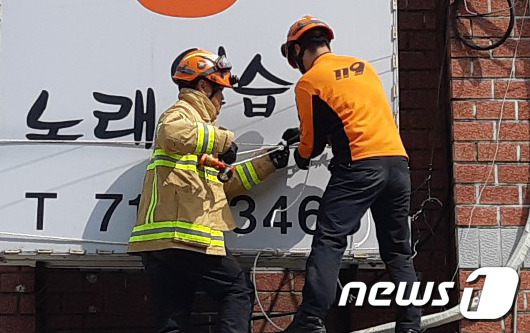 제주도 전역에 강풍주의보가 발효된 8일 오전 9시39분쯤 제주시 외도동의 한 간판이 흔들려 소방대원들이 안전조치를 취하고 있다.(제주도 소방안전본부 제공)© 뉴스1