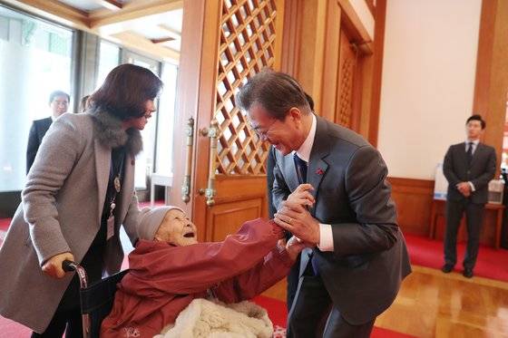 문재인 대통령이 2018년 4일 일본군 위안부 피해자들을 청와대로 초청해 오찬을 함께 했다. 문 대통령이 생전의 곽예남 할머니(지난해 3월 사망)의 손을 잡고 있다. 곽 할머니 휠체어를 미는 이가 당시 정의기억연대 이사장 윤미향 더불어시민당 비례대표 당선인이다. [사진 청와대]