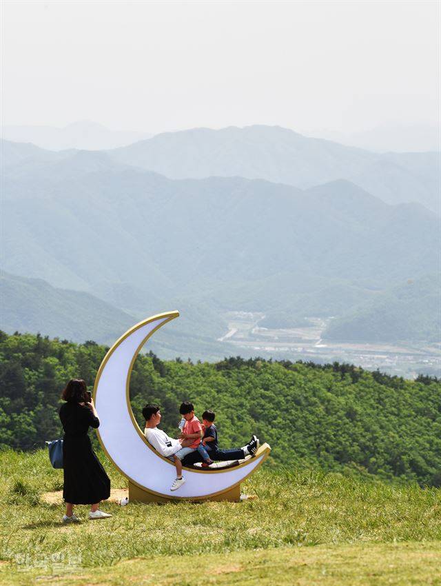 단산 정상에 설치된 초승달 모양 조형물에서 한 가족이 기념사진을 찍고 있다.