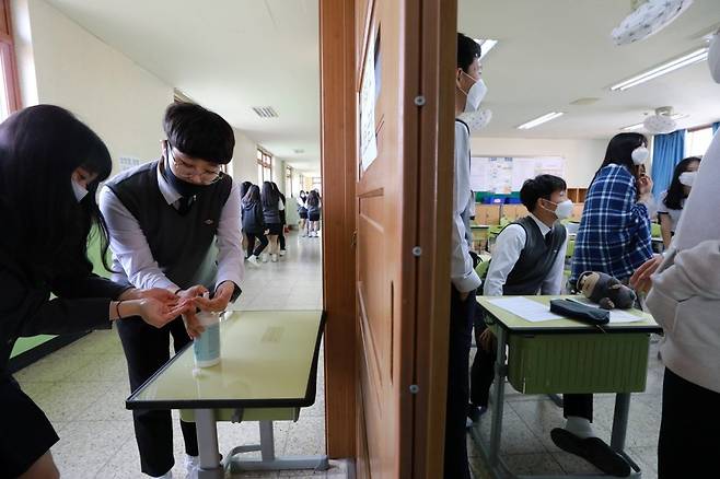 쉬는 시간에 학생들이 복도에서 손세정제로 손을 씻고 있다.