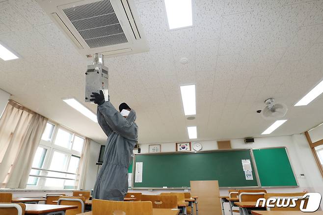 지난 11일 오전 서울 성동구 덕수고등학교에서 방역 전문가들이 개학을 앞두고 신종 코로나바이러스 감염증(코로나19) 확산 방지를 위해 방역을 실시하며 교실 에어컨에 소독약을 뿌리고 있다./뉴스1 © News1 민경석 기자