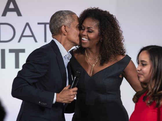 버락 오바마 전 대통령이 지난해 10월 오바마재단 행사 무대에 올라 부인 미셸 오바마의 볼에 입맞춤을 하고 있다.[AP=연합뉴스]