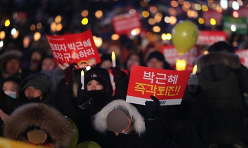 강추위가 몰아친 2017년 1월 14일 오후 서울 광화문 광장에서 열린 제12차 범국민행동의 날 행사에서 시민들이 촛불을 들고 탄핵을 촉구하고 있다.
