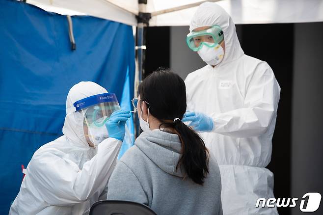 코로나19 선별진료소에서 방역당국 관계자들이 한 시민의 검체 채취를 하고 있다./뉴스1 © News1 유승관 기자