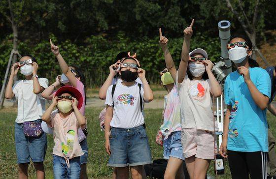 At a park on the bank of the Han River in Seoul, people observe the largest partial solar eclipse in eight years in Korea on Sunday afternoon. The moon moved between the Earth and the Sun at 3:53 p.m., with the transit to end at 6:04 p.m., the Gwacheon National Science Museum said. [NEWS1]