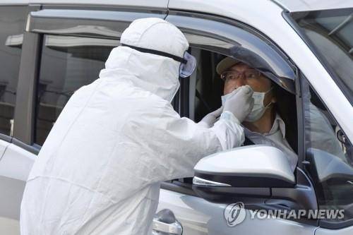 일본 오사카에 설치된 코로나19 검사소에서 의료진이 운전자의 검체를 채취하고 있다. [교도=연합뉴스 자료사진]