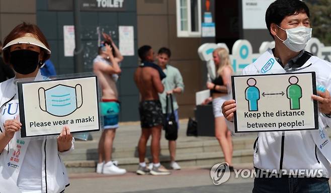 외국인들에게 방역수칙 무너진 해운대 (부산=연합뉴스) 손형주 기자 = 5일 오후 부산 해운대구 해운대해수욕장에서 부산시와 해운대구 관계자들이 외국인들을 대상으로 코로나19 거리 두기 캠페인을 벌이고 있다. 2020.7.5 handbrother@yna.co.kr