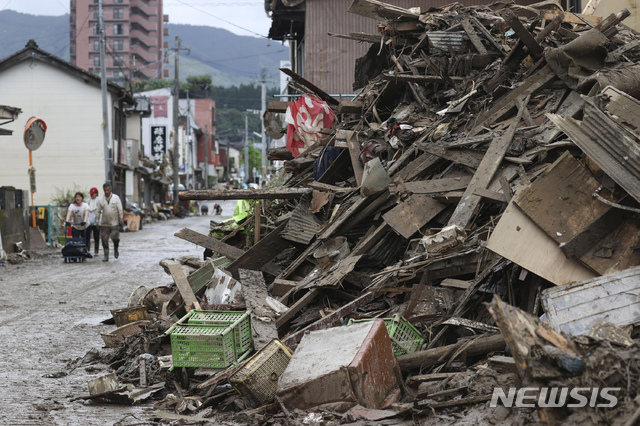 [히토요시=AP/뉴시스]6일 일본 구마모토현 히토요시에서 주민들이 폭우로 파괴된 잔해 옆을 지나고 있다. 2020.07.06.