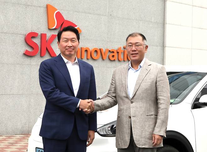 Hyundai Motor Group Executive Vice Chairman Chung Euisun (right) shakes hands with SK Group Chairman Chey Tae-won at SK Innovation’s electric vehicle battery plant in Seosan, South Chungcheong Province, Tuesday. (SK Group)