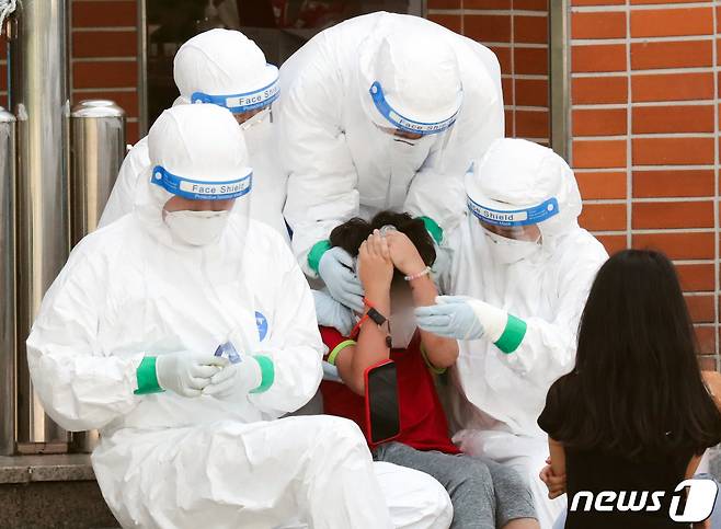 서지난 5일 서울 한 초등학교에 마련된 선별진료소에서 한 학생이 의료진의 도움을 받으며 검사를 받고 있다. /뉴스1 © News1 허경 기자