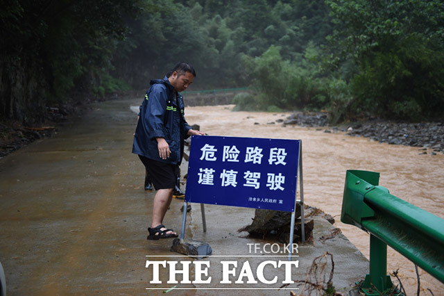 안후이성 후이저우의 한 도로가 폭우로 파손된 가운데 관계자가 경고문구를 설치하고 있다.