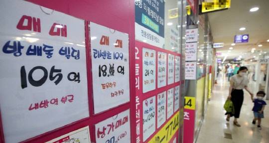 한 시민이 자녀와 함께 아파트 급매물 시세가 걸려있는 부동산공인중개업소 앞을 지나가고 있다.<연합뉴스>