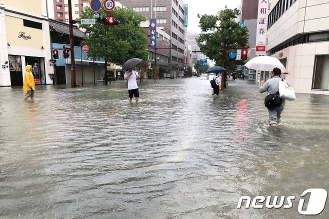 지난달 28일 일본 규슈지역 사가현에 기록적인 폭우가 쏟아진 거리에서 주민들이 걸어가고 있다. 일본 기상청은 이날 사가현 등에 '호우 특별 경보'를 발령하고 48만여명에게 대피령을 내렸다. © afp=뉴스1 © News1 우동명 기자
