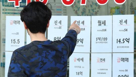 한 시민이 부동산공인중개업소에 걸린 아파트 급매물 시세를 가리키고 있다.<연합뉴스>
