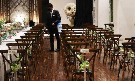 경기도가 지난 1일 결혼식장 등에 집합제한 행정명령을 내린 이후 처음 맞이한 주말인 7일 경기도 수원시 팔달구 파티움하우스에서 직원이 예식 시작에 앞서 신종 코로나바이러스 감염증(코로나19) 예방을 위한 거리 두기를 위해 1m 이상 간격을 유지해 배치한 하객 의자 사이를 소독하고 있다. 연합뉴스