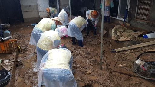 6일 충북 제천의 한 침수주택에서 자원봉사자들이 우비를 입고 토사를 걷어내고 있다. 충북도 제공