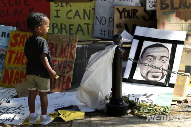 [새크라멘토=AP/뉴시스]6월 19일(현지시간) 미 캘리포니아주 새크라멘토에서  '준틴스데이'(Juneteenth Day) 기념 집회가 열린 가운데 2세 소년이 조지 플로이드의 얼굴 그림을 바라보고 있다. / 사진 = 뉴시스