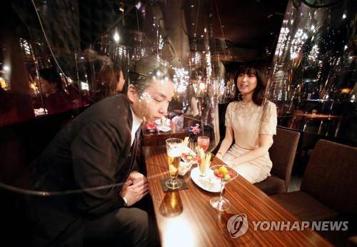아크릴 차단막 사이로 접객하는 여성 종업원 (도쿄 로이터=연합뉴스) 6일 일본 도쿄도(東京都) 긴자(銀座)에 있는 한 주점에서 여성 종업원이 아크릴 막을 사이에 두고 남성 손님을 접대하고 있다. 2020.8.8