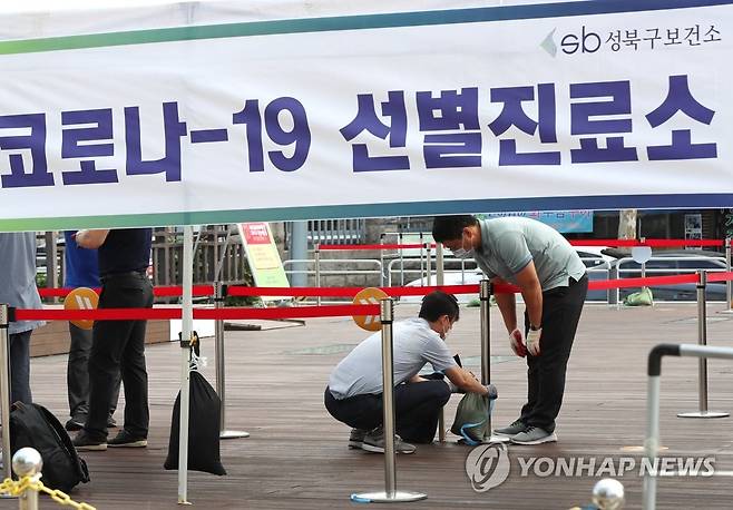 태풍 대비하는 성북구 선별진료소 (서울=연합뉴스) 이정훈 기자 = 26일 오전 서울 성북구청 앞 바람마당에 설치된 코로나19 선별진료소에서 구청 직원들이 강풍에 대비해 모래주머니를 매달고 있다.  uwg806@yna.co.kr