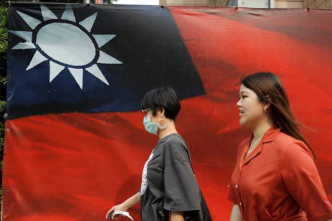 지난 10일(현지시간) 대만 수도 타이페이 시민들이 대만 국기 앞을 걸어가는 모습. [로이터]