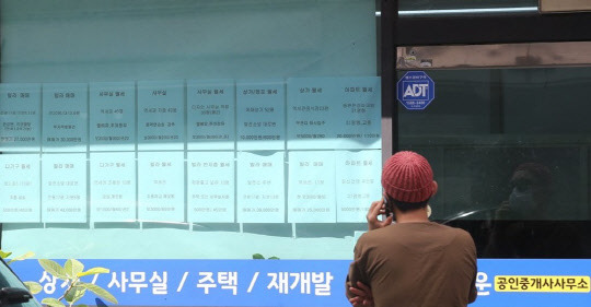 한 시민이 부동산공인중개업소 게시판에 걸린 급매물 시세를 살펴보고 있다.<연합뉴스>