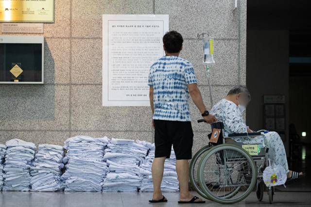 23일 서울 송파구 서울아산병원 로비에서 환자와 보호자들이 전공의들이 벗어놓은 의사 가운 위로 붙은 입장문을 바라보고 있다. 뉴스1
