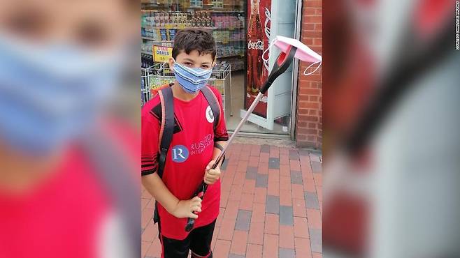 9세 소년 조조 아이소이가 거리에서 집게로 수거한 마스크를 들어보이고 있다.(사진=샬럿 러베니 제공)