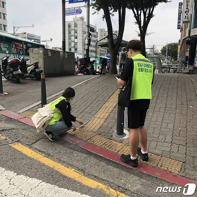 성남시 장애물 없는 생활환경 조사단이 수진동에서 휠체어 진입 도로의 길이를 재고 있다.(성남시 제공) /© News1
